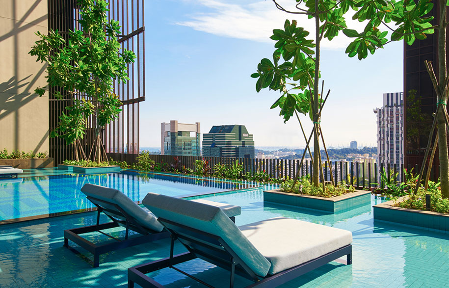The distinctive red mesh facade of Oasia Hotel Downtown covered in lush green vines
